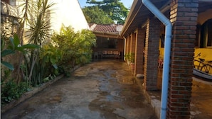 A narrow pathway leading to a covered area with brick walls and potted plants. - Casa na praia do Romance Caraguatatuba (Caraguatatuba)