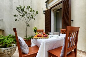 A table set with a fruit basket, a wine glass, and a small potted plant. - B&B Palazzo Corcioli (Mesagne)