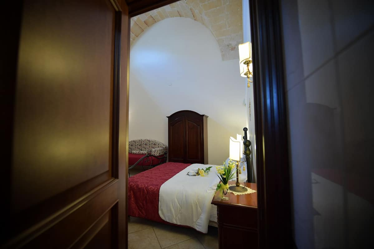 Ein Schlafzimmer mit einem Bett, einem Nachttisch, einer Lampe und einem Holzschrank.