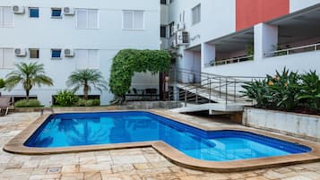 Una piscina al aire libre, sillones reclinables de piscina