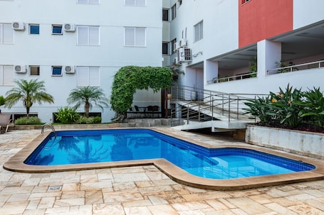 Una piscina al aire libre, sillones reclinables de piscina