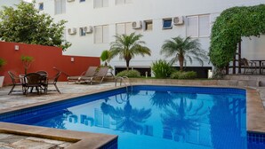 A swimming pool with lounge chairs and palm trees. - Lindoya Hotel (Catalao)