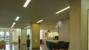 A modern lobby with a reception desk, seating area, and large windows. - Lindoya Hotel (Catalao)