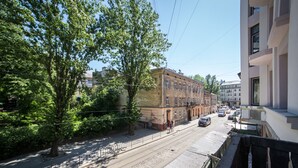 En gatubild med en byggnad som har en rad fönster och ett träd i förgrunden.