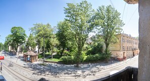 Straßenszene mit einer Straßenbahn, Bäumen und einem Gebäude mit einer roten Markise.