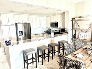 A modern kitchen with white cabinets, stainless steel appliances, and a central island with bar stools.