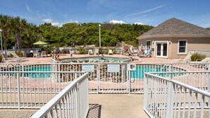 A pool area with two pools, a covered barbecue area, and a building with a sloped roof. - July 27-Aug 1 open.  Modern Condo—Best location—beach, Ft Clinch & downtown. (Fernandina Beach)