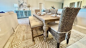 A dining area with a wooden table, upholstered chairs, and a patterned rug. - July 27-Aug 1 open.  Modern Condo—Best location—beach, Ft Clinch & downtown. (Fernandina Beach)