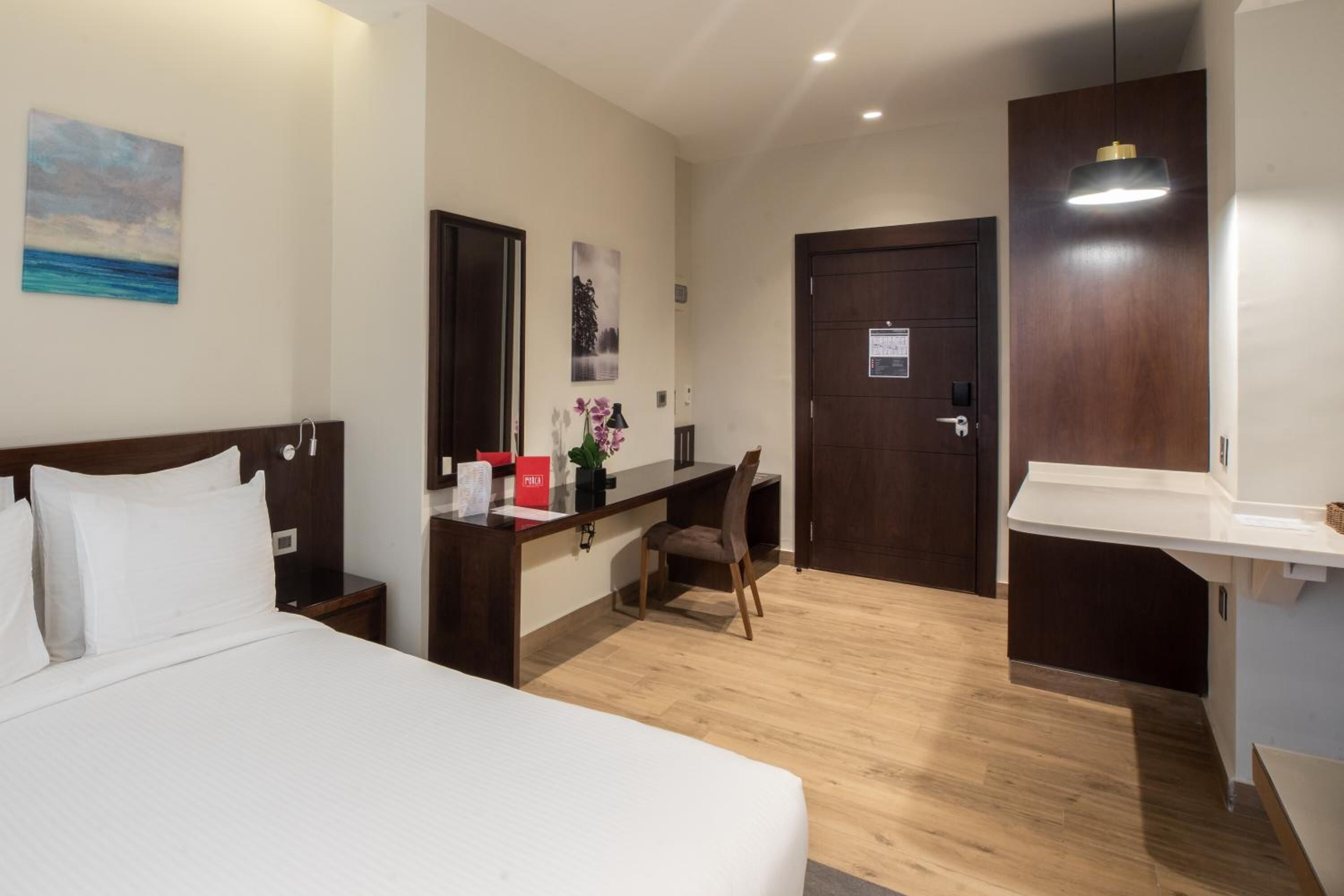 Una habitación de hotel con cama, escritorio, silla y puerta.