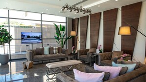 Un salón moderno con un televisor grande, sofás cómodos, una mesa de centro y un ventanal con vistas al mar.