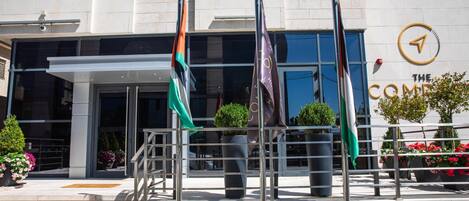A modern building with a glass entrance, multiple flags, and a sign reading "The Compass."