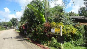 A rural road with a sign for a laundry service and a room sign. - Grandma's Home Sangkhlaburi (Sangkhla Buri)