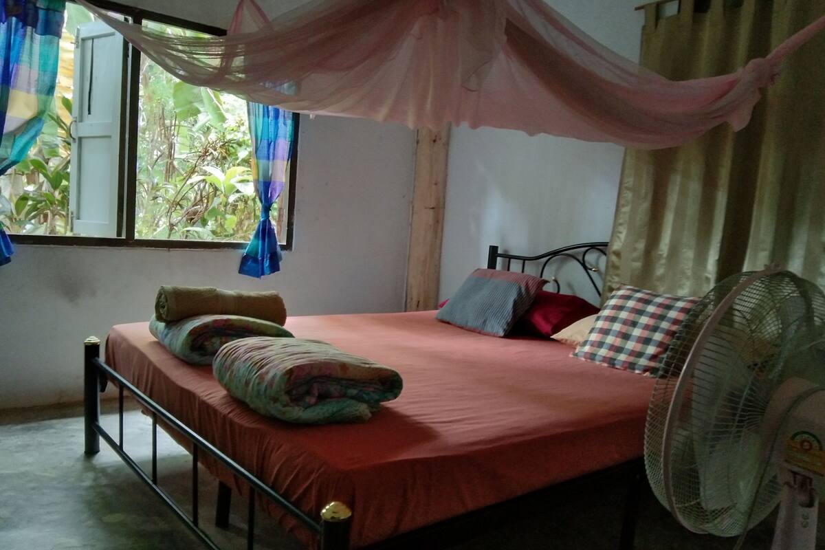 Quarto com cama, ventoinha e cortinas.