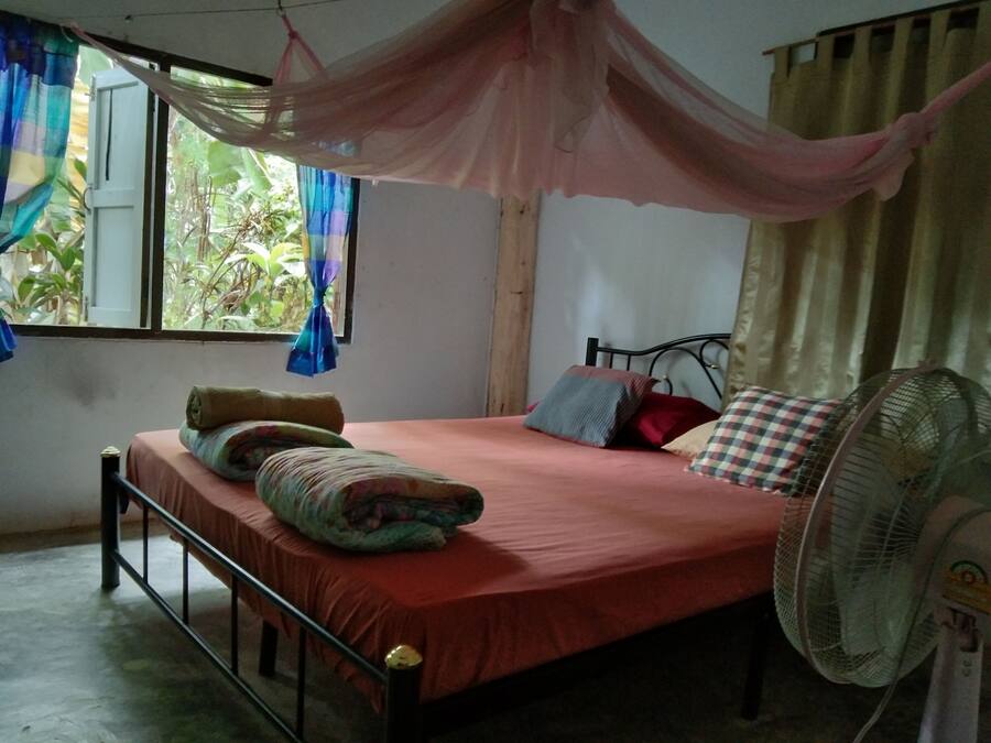 Une chambre à coucher avec un lit, un ventilateur et des rideaux.