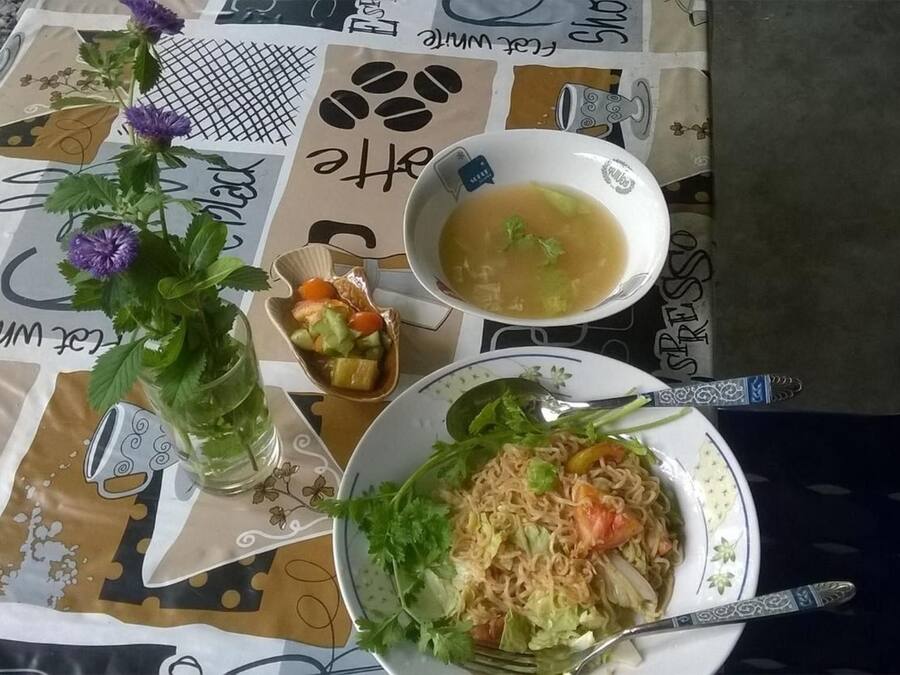 Una mesa con una taza de café, un tazón de sopa y un plato de fideos.