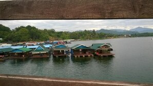 Floating houses with green roofs on a calm lake, surrounded by lush greenery and mountains. - Grandma's Home Sangkhlaburi (Sangkhla Buri)