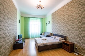 Cozy retreat with a large bed, television, and dresser, set against a patterned backdrop.