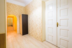 Stylish hallway with a floral patterned wallpaper, wooden floor, and a door leading to another room.