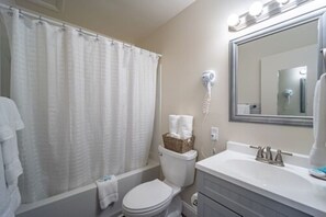 A bathroom with a shower curtain, a toilet, a bidet, a sink, and a mirror. - Ocean Glass Inn (Rehoboth Beach)
