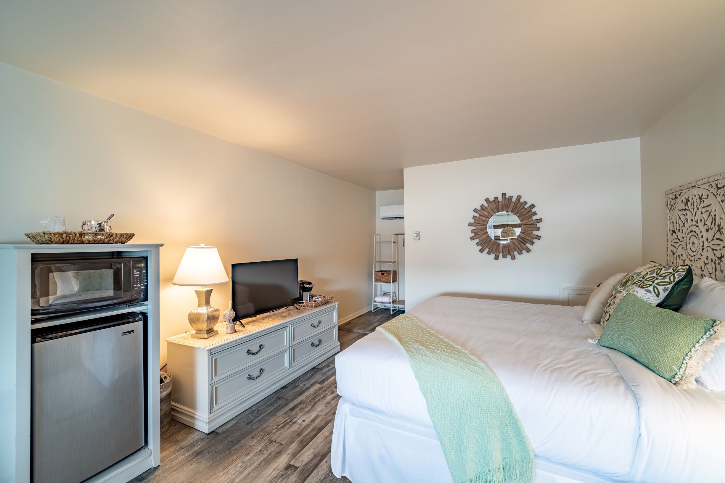 A hotel room with a bed, a TV, a microwave, and a refrigerator.