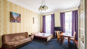A room with a bed, a sofa, a dining table, and purple curtains. - Apartments on Square Rynok on Theatralna Street (Lviv)