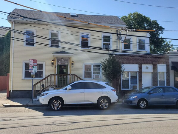 A two-story building with a beige exterior, a front entrance with a wooden porch, and a sign indicating 'The Windsor Inn' with a 'No Parking Anytime' sign. - The Windsor Inn (Cambridge)