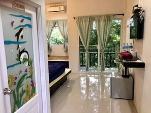 A hotel room with a bed, a small desk with a keyboard, a mirror, and a window with curtains. - Chillchill (Sangkhla Buri)