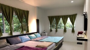 Un dormitorio moderno con una cama grande, dos ventanas con cortinas, una mesita de noche y un televisor de pantalla plana en la pared.