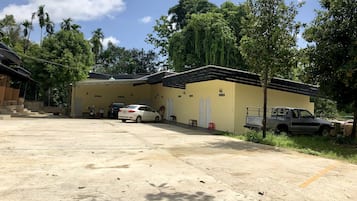 A parking area with a yellow building, a white car, and a truck.
