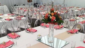 A banquet hall with round tables set for a formal event, featuring white tablecloths, clear glassware, and pink napkins. - Borrowdale Country Manor (Harare)