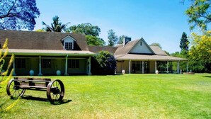A large house with a covered porch and a carriage in the front yard. - Borrowdale Country Manor (Harare)