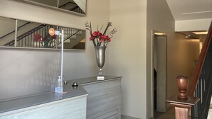 Un hall d’hôtel moderne avec un comptoir d’accueil, un grand miroir et un escalier.
