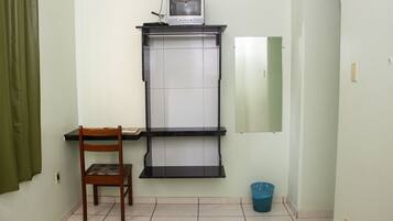 A small room with a desk, chair, and a television on a shelf.