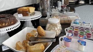 Un buffet proposant une variété de plats, notamment des gâteaux, des pâtisseries et des boissons.