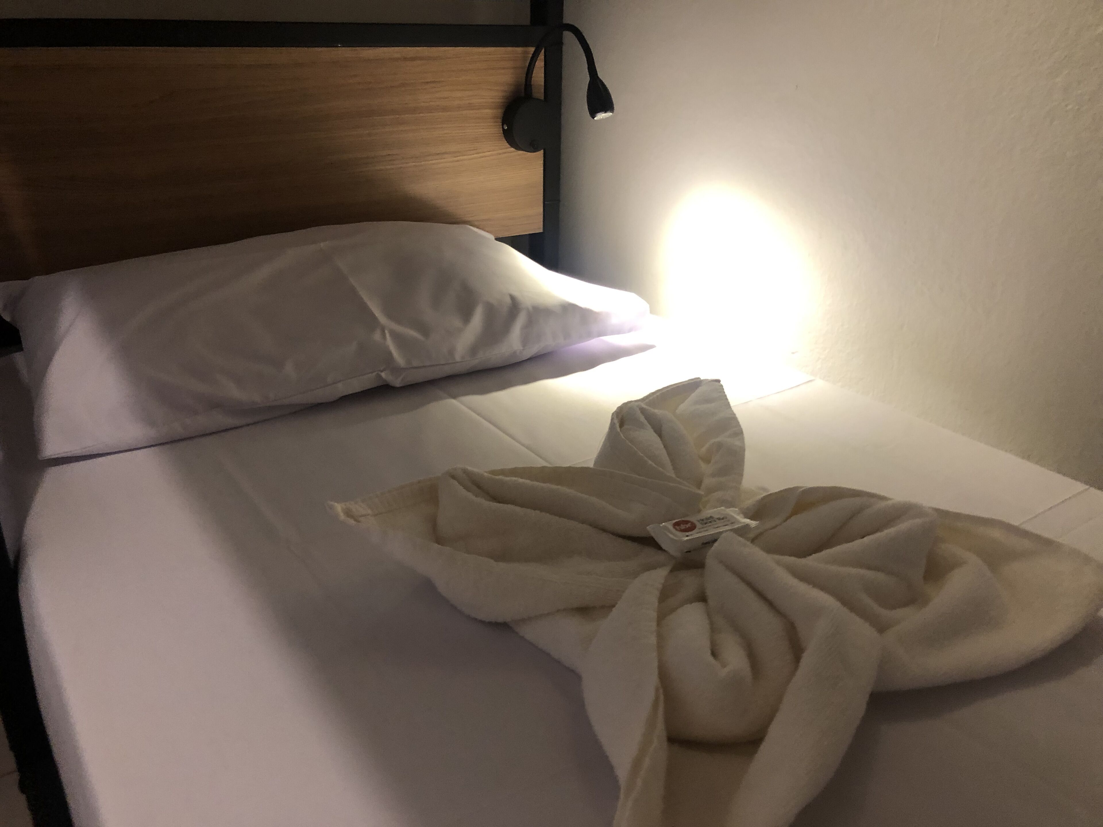 A bed with white bedding and a blanket folded in the center.