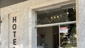 L’entrée d’un hôtel, avec une enseigne indiquant « HÔTEL » et un avis interdisant l’accès sans masque.