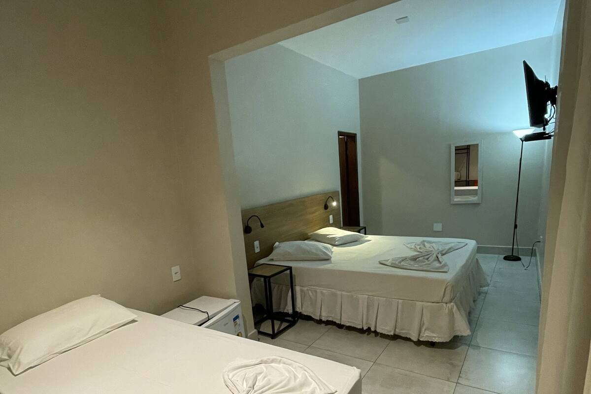 Ein Hotelzimmer mit zwei Betten, einem Schreibtisch, einem Stuhl, einer Lampe und einem Spiegel.