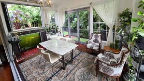 Une pièce spacieuse avec une grande table à manger, des chaises confortables, un aquarium et une vue sur un jardin luxuriant grâce à de grandes fenêtres.