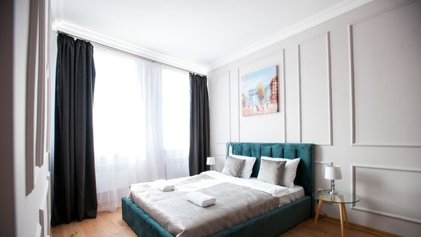 Un dormitorio ordenado con una cama, una mesita de noche y un cuadro en la pared.