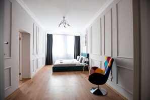 Ein Hotelzimmer mit Bett, Stuhl, Nachttisch und einem Fenster mit Vorhängen.