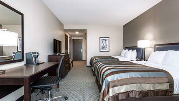 A hotel room with a desk, two beds, a TV, and a large mirror.