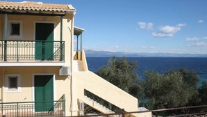 Un edificio de dos plantas con un balcón, una escalera y vistas al mar.