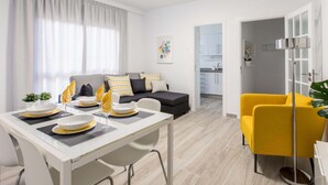 Ein modernes Wohnzimmer mit Essbereich, einer Couch und einem gelben Sessel.