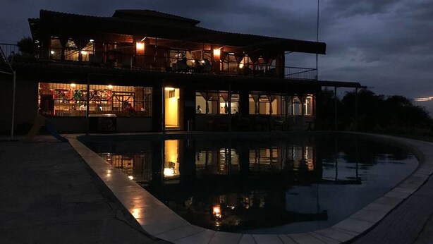 Ein zweigeschossiges Haus mit einem Schwimmbad im Vordergrund.