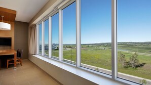Ein modernes Zimmer mit großem Fenster, einer Essecke und einem Flachbildfernseher.