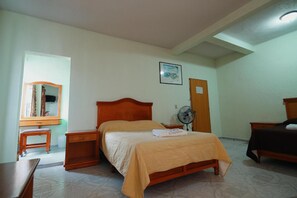 A bedroom with a wooden bed, bedside tables, a mirror, a fan, and a small desk. - Hotel El Conquistador Monarca (Zitácuaro)