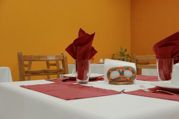 Una mesa de comedor dispuesta con servilletas rojas, un vaso y un adorno.