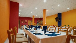 A dining area with tables set for a meal, chairs, and a television mounted on the wall. - Hotel El Conquistador Monarca (Zitácuaro)