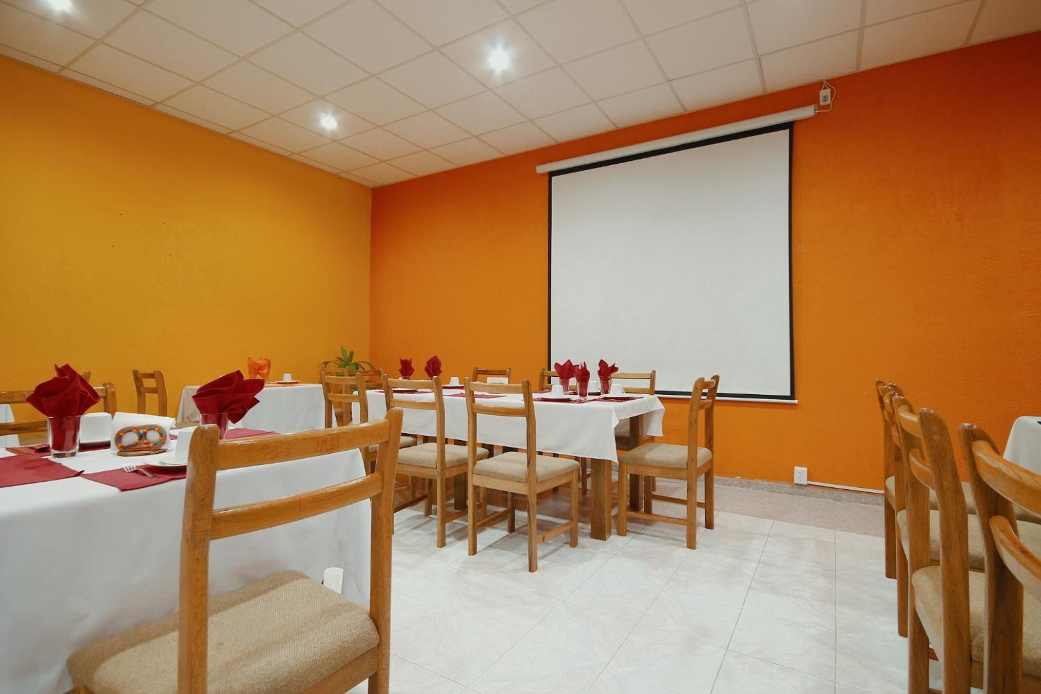 A conference room with tables set for a meeting, a projector screen, and a whiteboard.