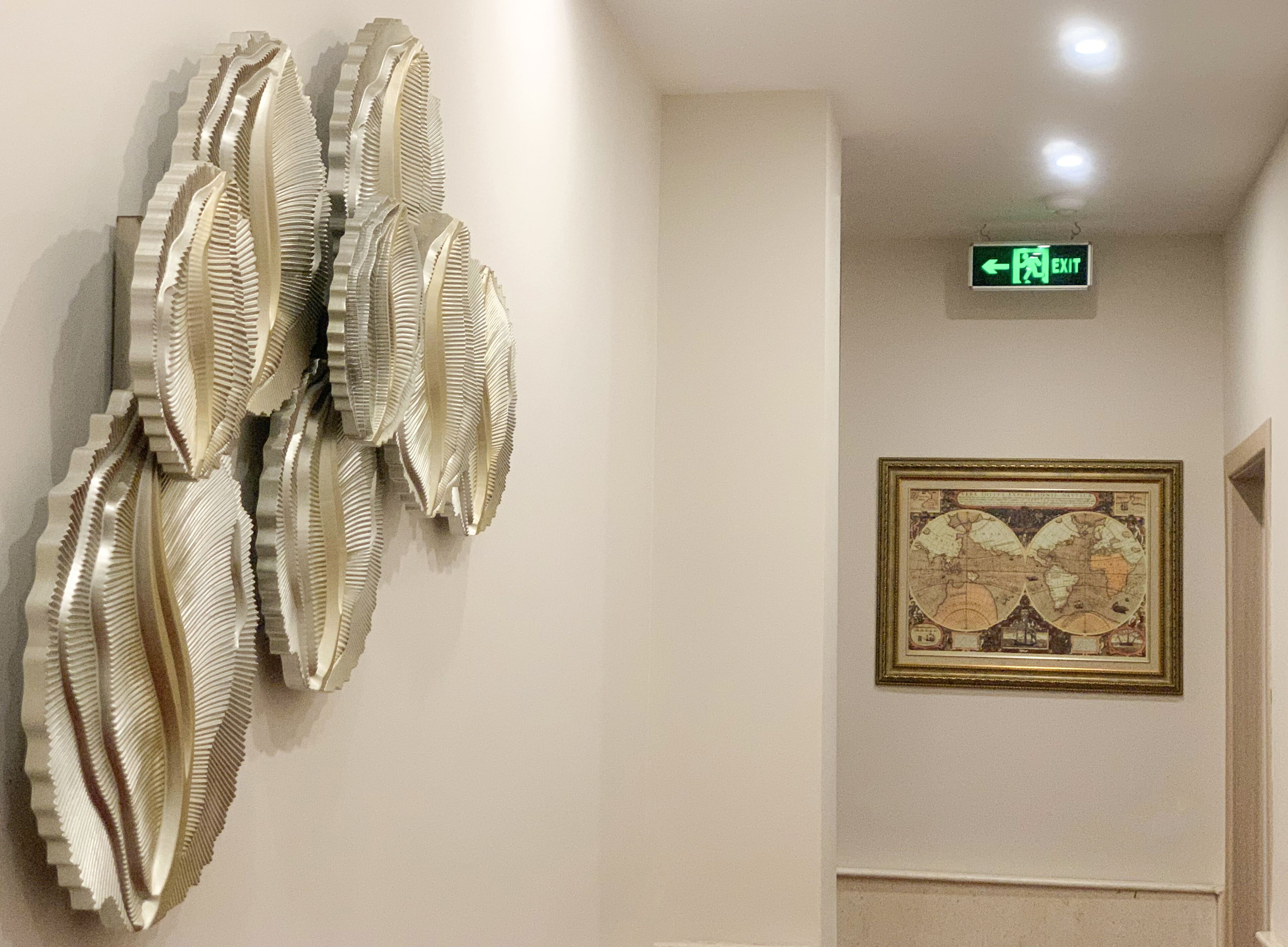 A wall with a framed map and a wall-mounted exit sign.